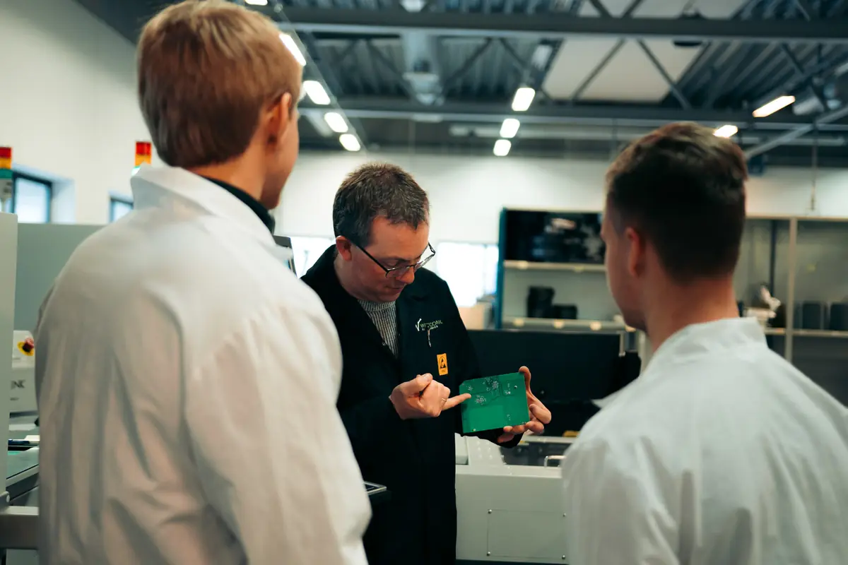 Three engineers discussing a circuit board